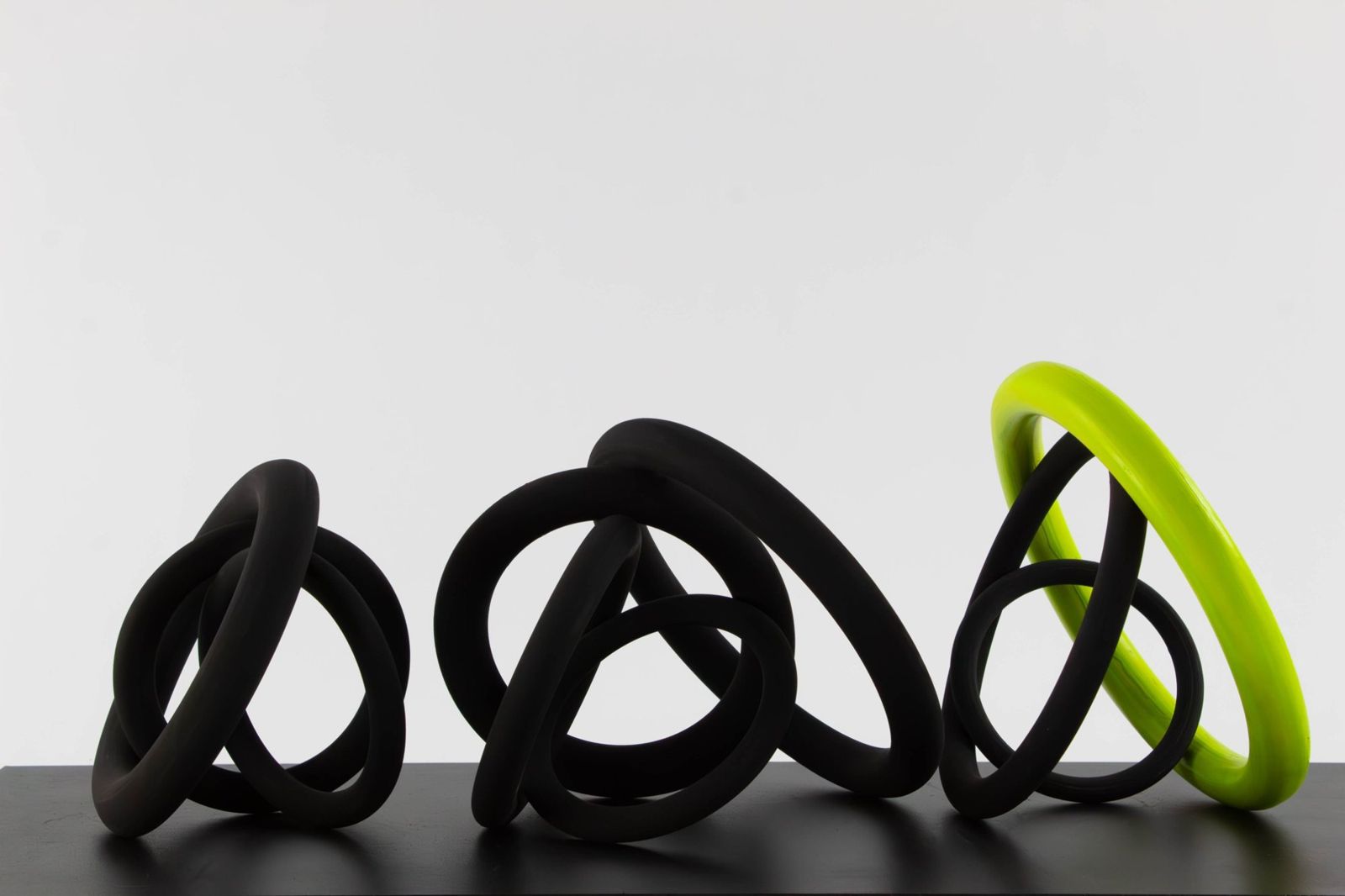 Three knots of matte black porcelain rings with one chartreuse ring
