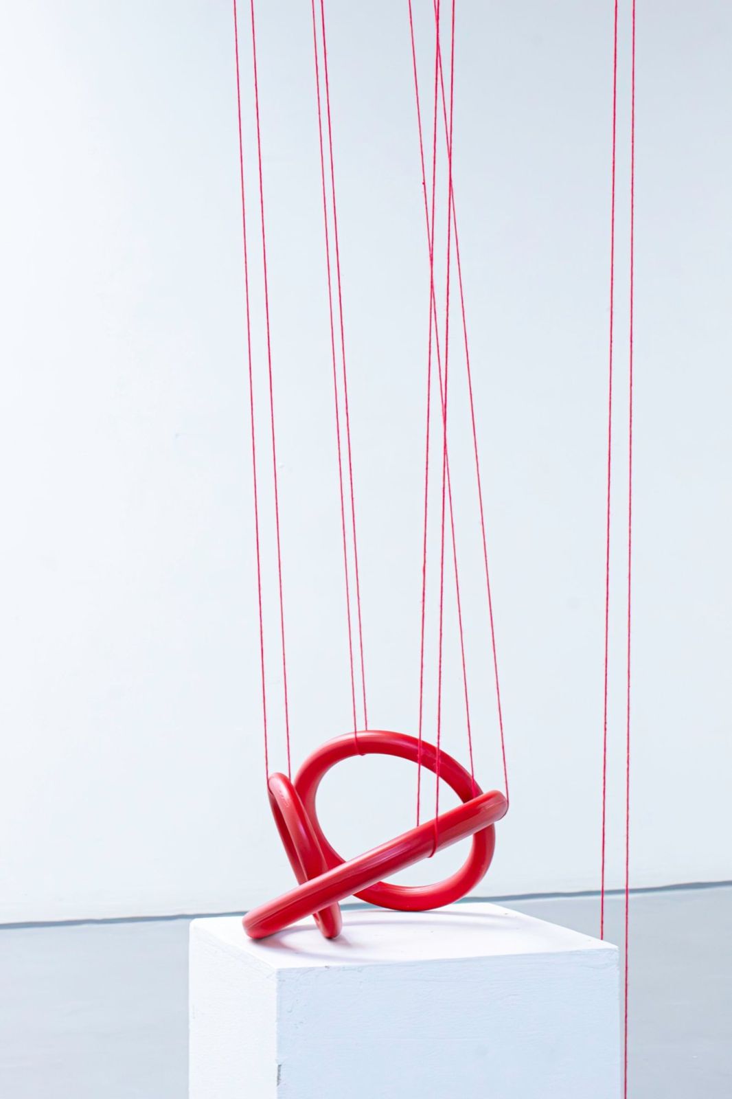 Red porcelain ring knot held up by long red threads