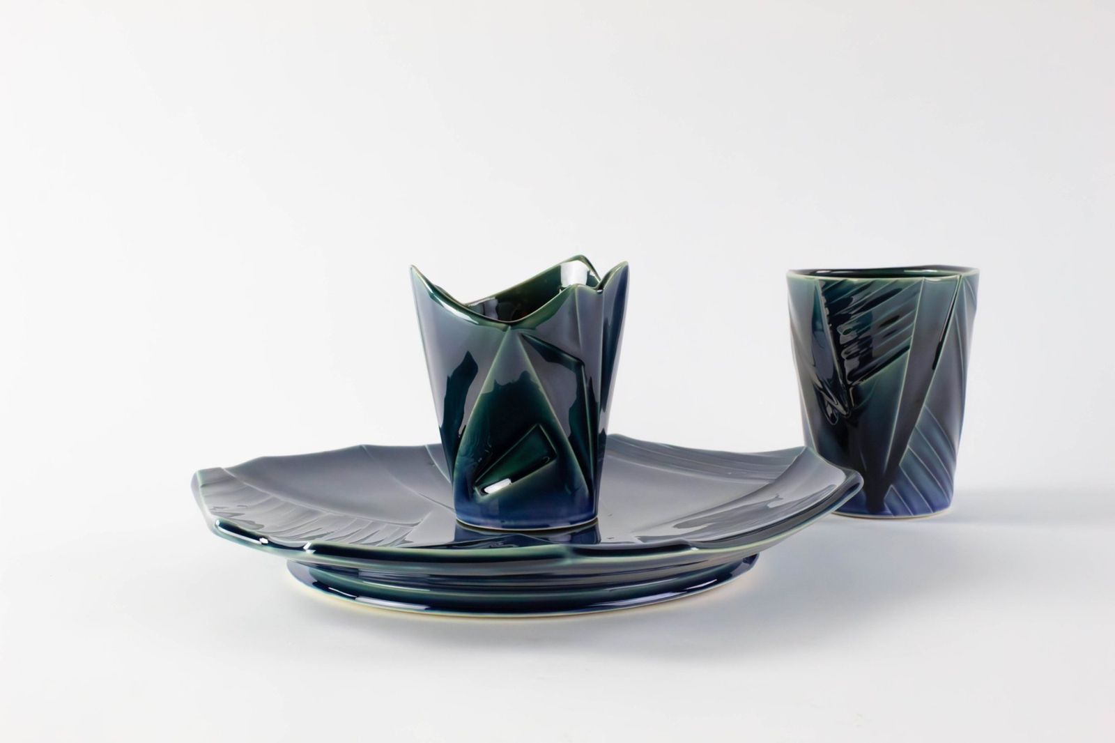 Folded blue-green porcelain cup on an angular plate