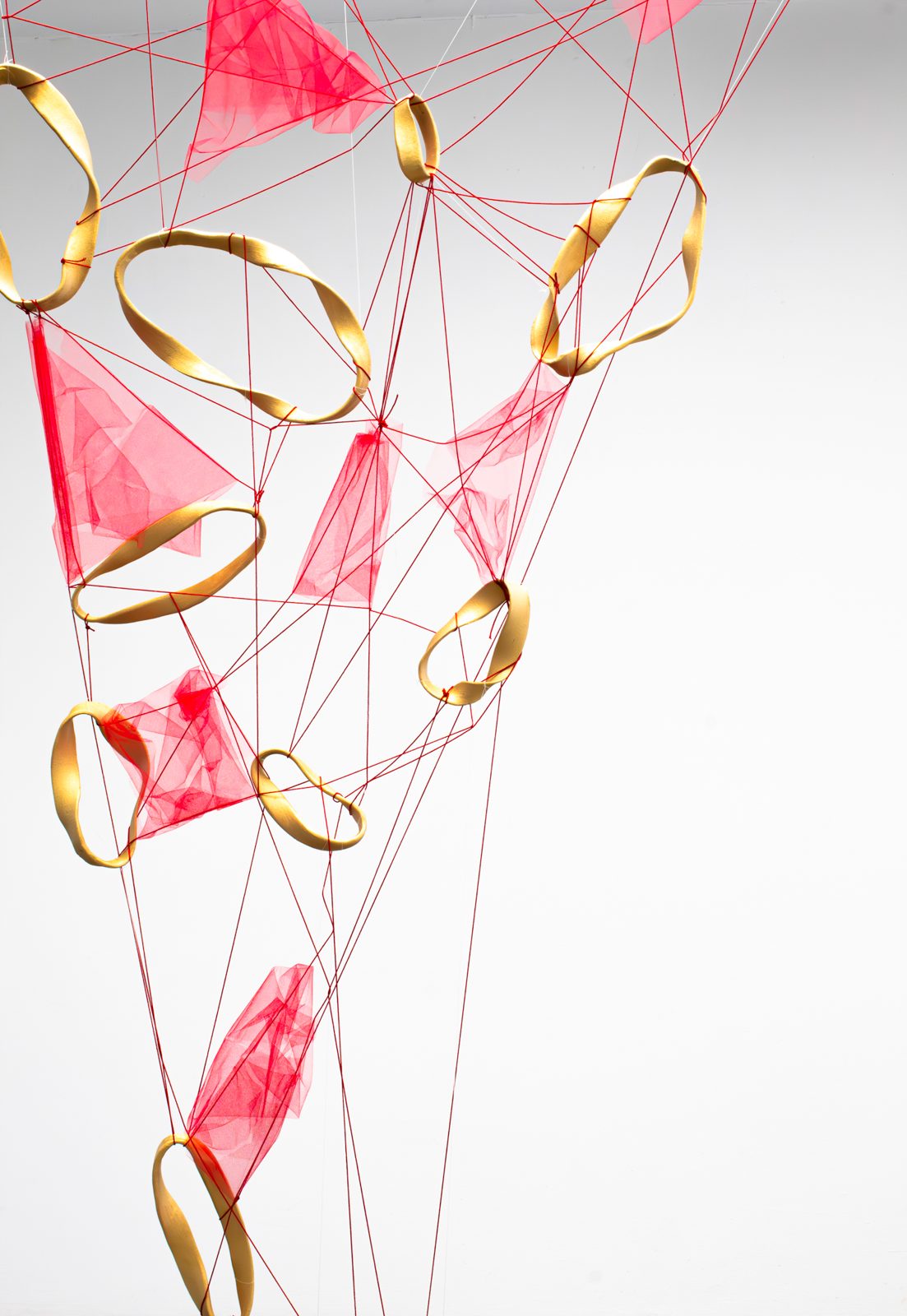 Close view of gold porcelain rings, red thread and pink tulle