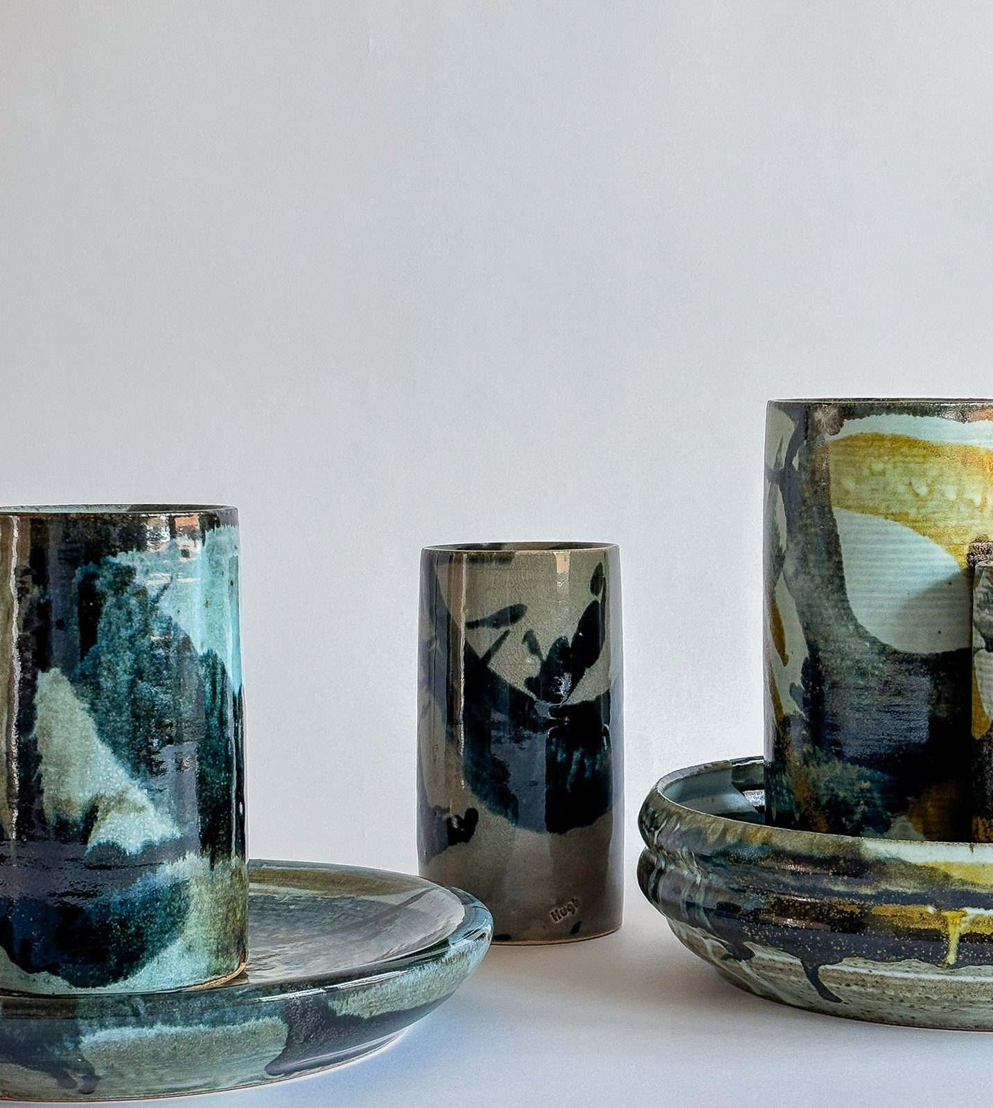 Painted cylinders and plates in blue, green and ochre glazes