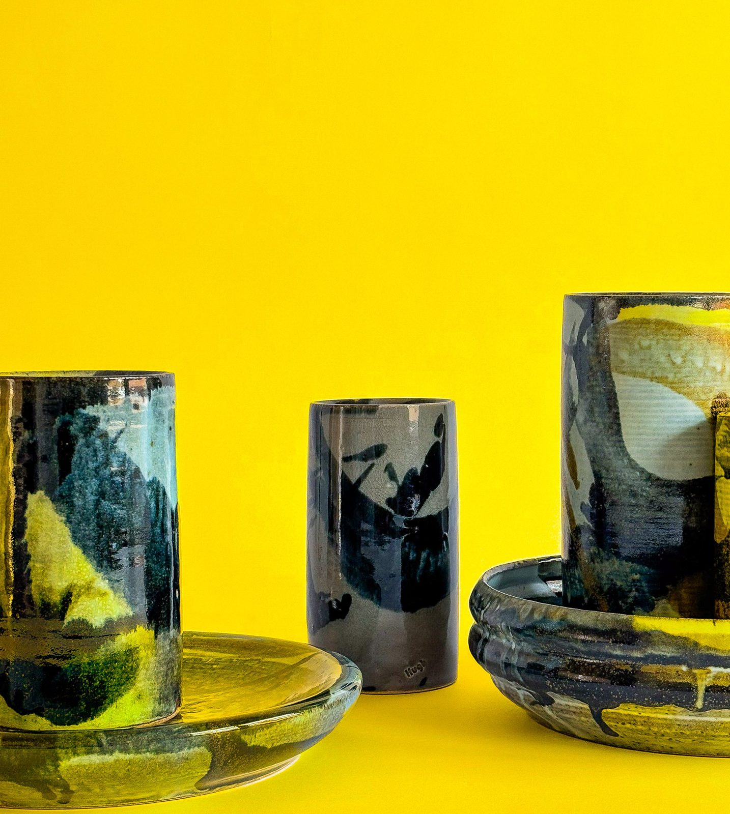 Painted cylinders and plates against yellow