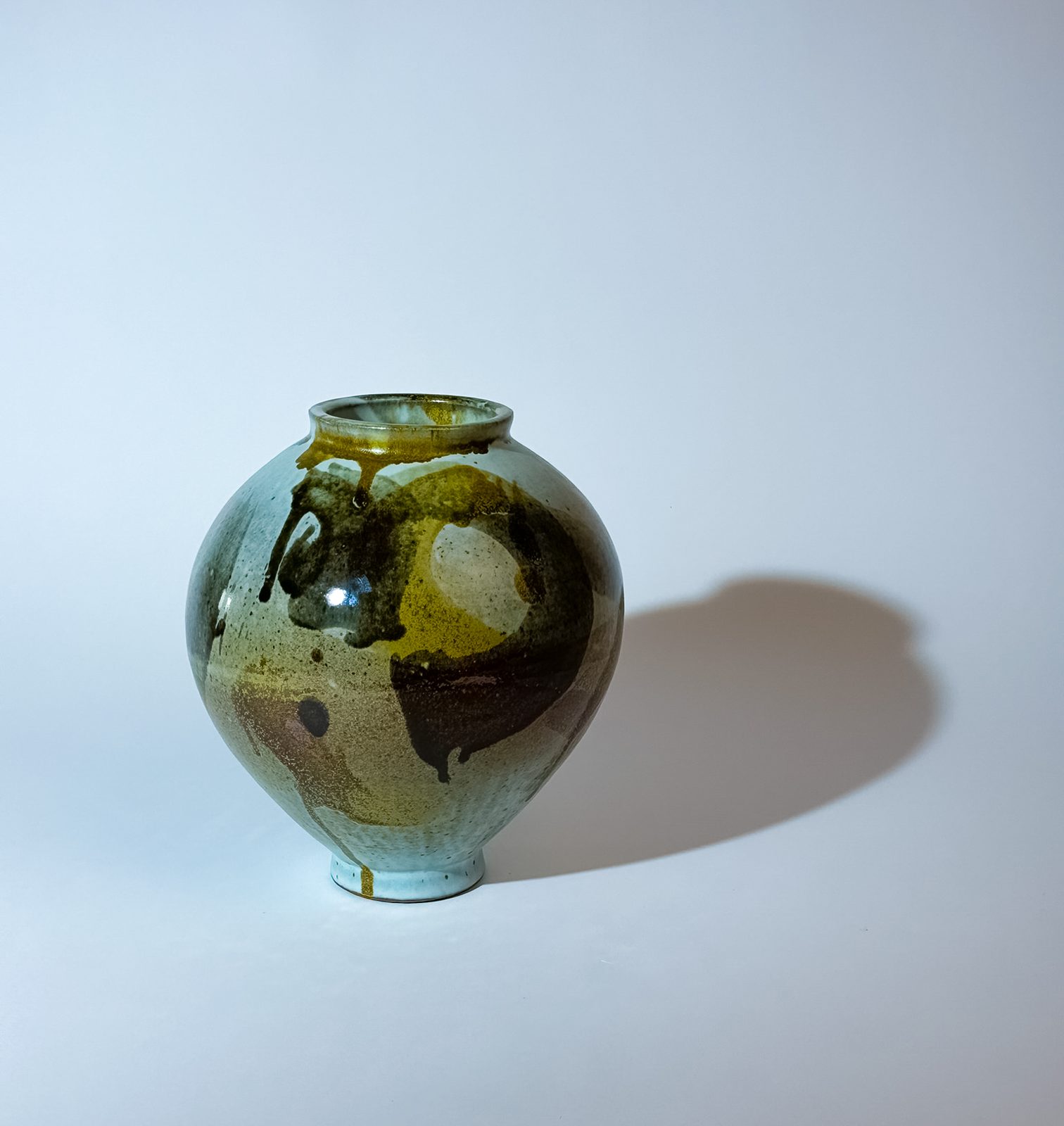Moon jar painted in pale blue, ochre and dark brown glazes