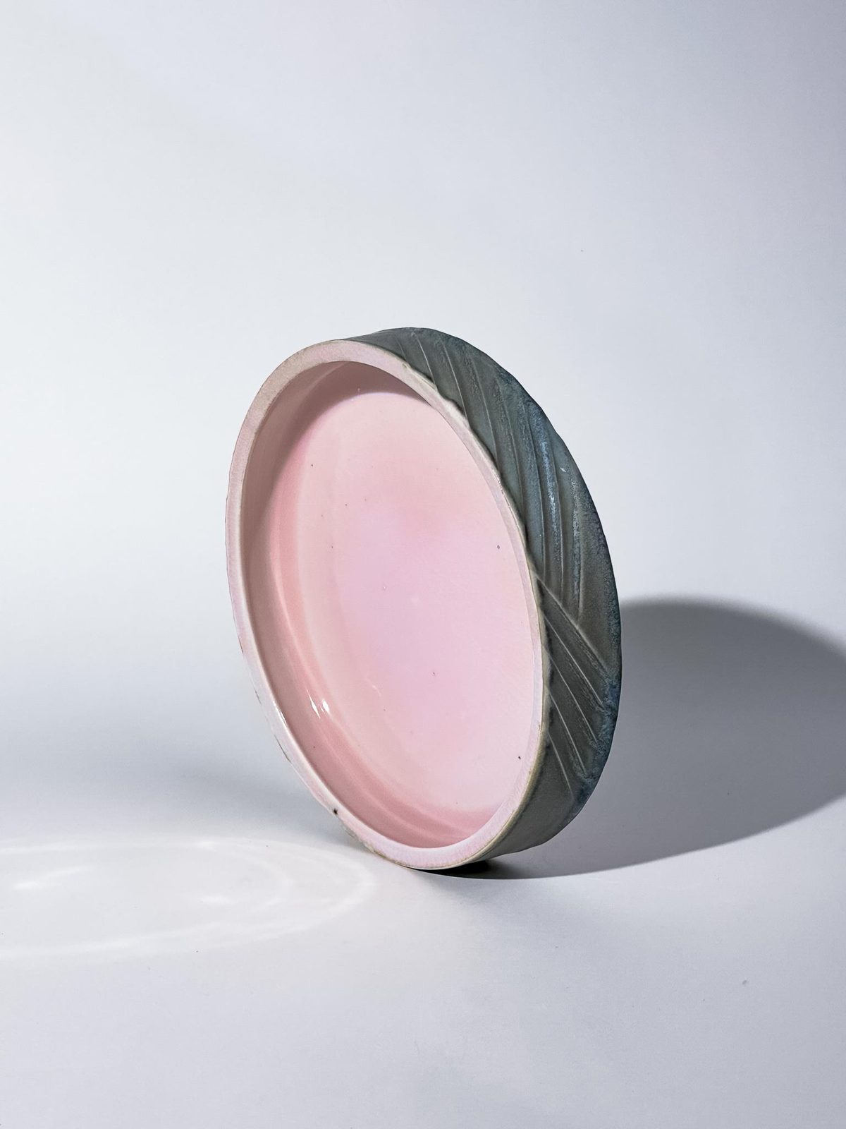 Shallow dish with a pink interior and carved grey-green rim